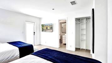 Un dormitorio con dos camas, un armario y una puerta que da al baño.