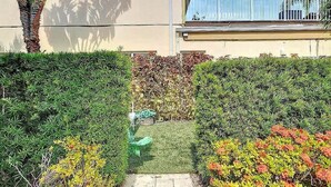 Un giardino curato con un vialetto, diversi arbusti e un edificio con un balcone.