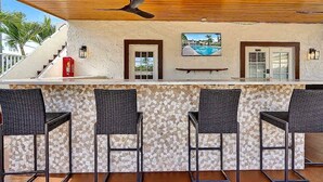 Un'area bar all'aperto con ventilatore a soffitto, una scala e vista sulla piscina.