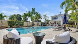 A poolside area with wicker lounge chairs and a pool. - Bright Studio Retreat w/ Kitchen at Lake Worth (Lake Worth Beach)