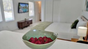 A room with a bed, a dresser, a bowl of red roses, and a framed picture on the wall. - Bright Studio Retreat w/ Kitchen at Lake Worth (Lake Worth Beach)