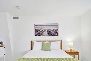 Une chambre à coucher avec un lit, une table de chevet avec une lampe et un tableau encadré au mur.