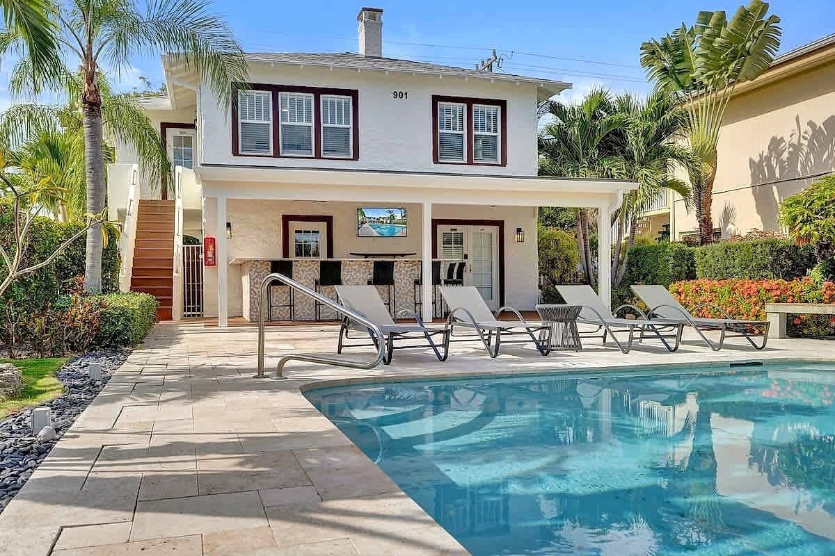 A two-story building with a pool area, including lounge chairs and a covered seating area.