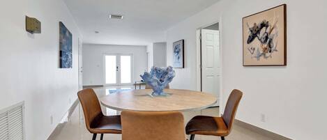 A modern dining area with a round table, two brown chairs, and a decorative centerpiece.