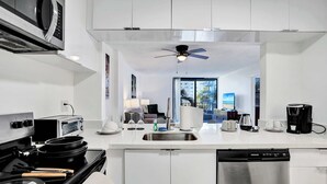 Een moderne keuken met een vaatwasser, kookplaat, magnetron en een plafondventilator.