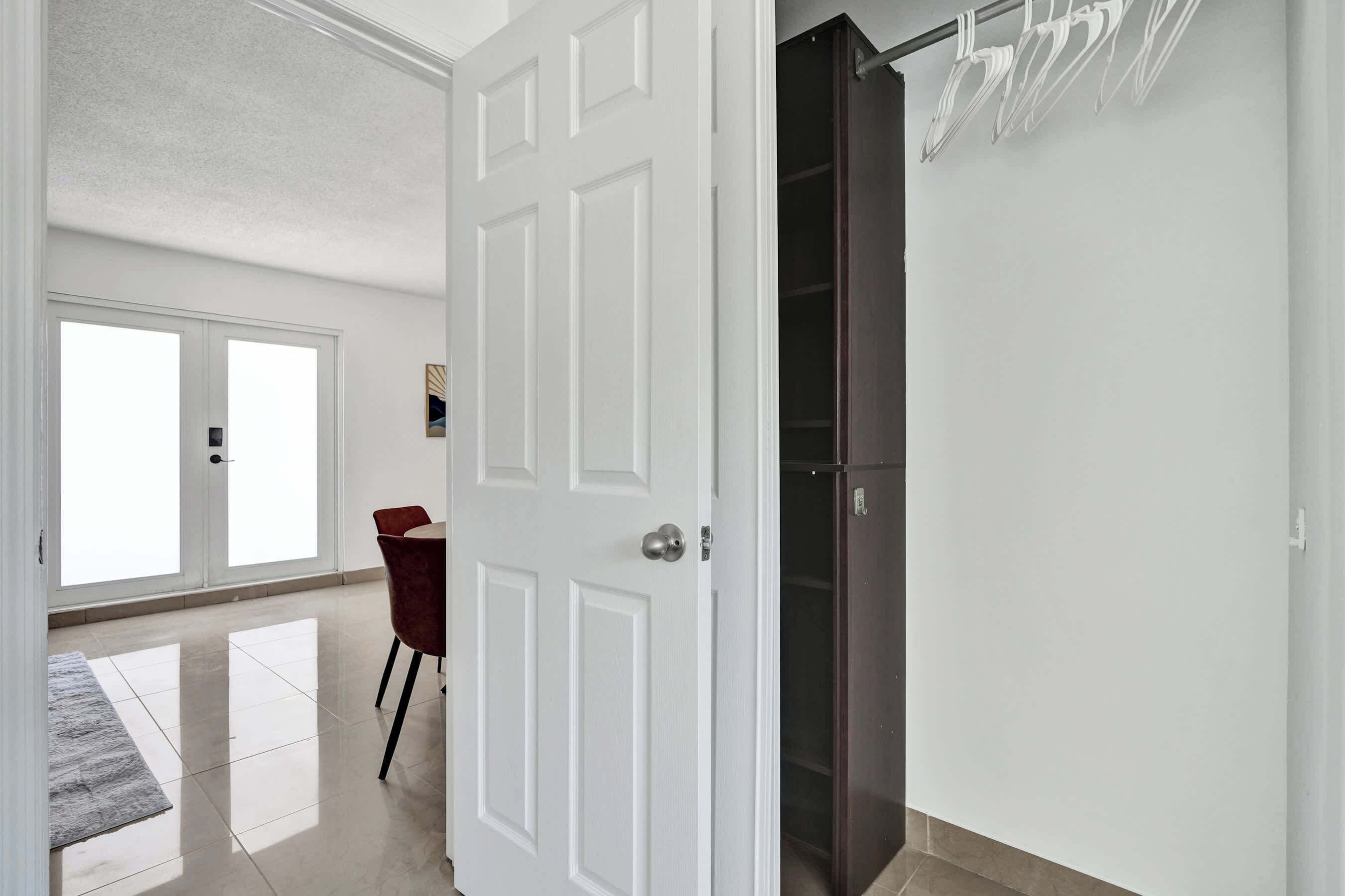 Una habitación con una puerta blanca, un armario oscuro y una silla roja.