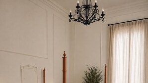 A four-poster bed with a wooden frame, a chandelier, a potted plant, and a view of a curtain. - Dimora di Duen (Villa San Giovanni)