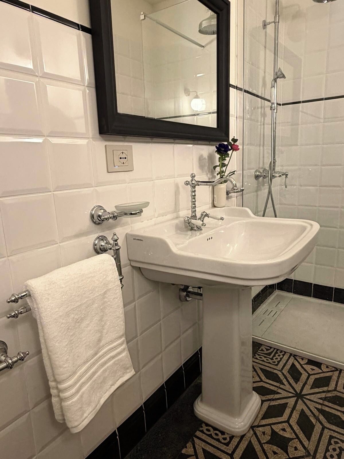 A bathroom with a white sink, a towel rack, a mirror, and a shower.