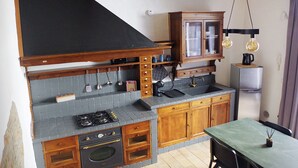 Une cuisine équipée d’une cuisinière à gaz, d’un four, de meubles en bois et d’un dosseret carrelé.