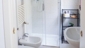 Une salle de bain avec deux lavabos, une douche et une porte en verre.