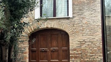 A stone building with a large wooden door and a window above it.