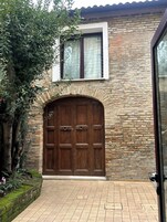 Un edificio in pietra con un'ampia porta di legno e una finestra sopra.