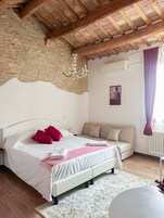 Una camera da letto con un letto, un divano, un lampadario e un termosifone.