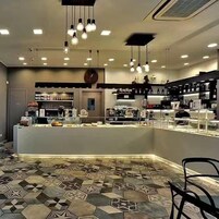 Un área de bar moderna con una barra, lámparas colgantes y un suelo con diseño.
