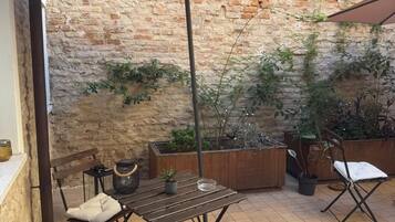 An outdoor patio with a brick wall, a table with chairs, and a large umbrella.
