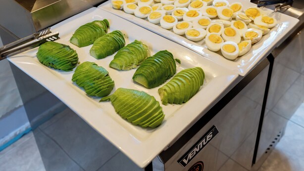 A buffet with various food items, including avocado slices and hard-boiled eggs.