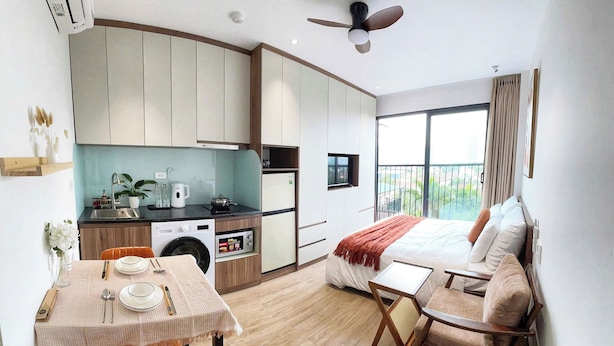 A modern kitchen with a dining area, a sofa, and a balcony with a view. - Hanoi Aurelia Stay (Hanoi)