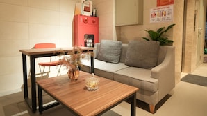 A modern living area with a wooden coffee table, a grey sofa, a red cabinet, and a potted plant. - Hanoi Aurelia Stay (Hanoi)