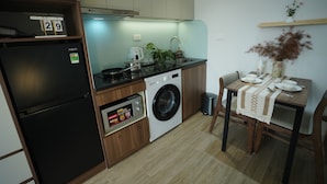 A compact kitchen with a refrigerator, washing machine, and a dining area with a table set for two. - Hanoi Aurelia Stay (Hanoi)