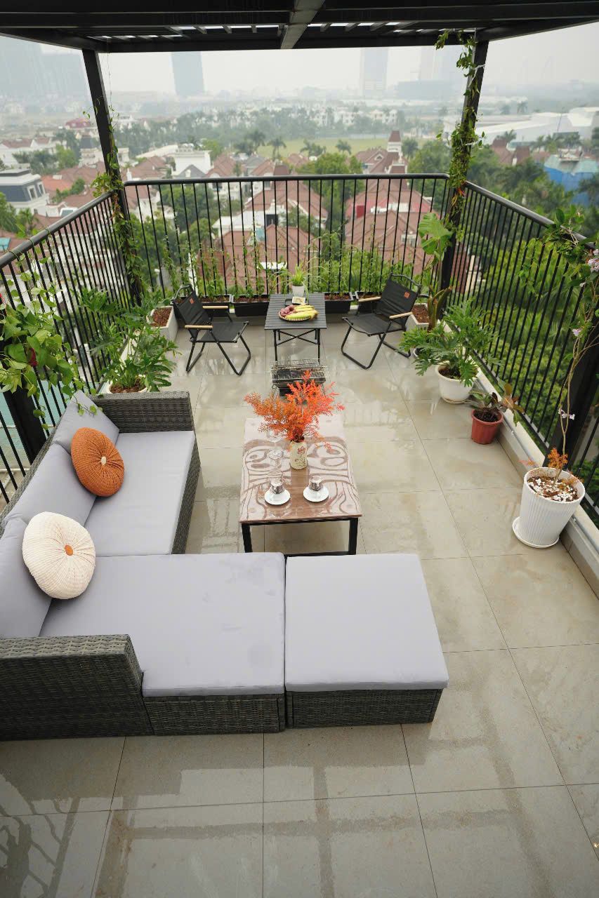 Una terraza en la azotea con sofá, mesa, sillas y plantas en macetas.