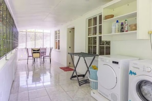 A laundry area with a washing machine, a table, and chairs.