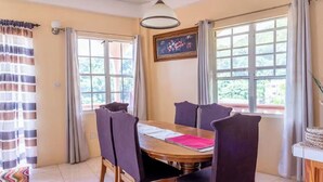 Zona pranzo con tavolo in legno, sei sedie e un quadro appeso alla parete.