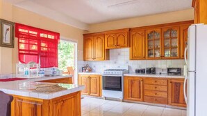 Una cucina con mobili in legno, un'isola centrale, un fornello e un frigorifero.