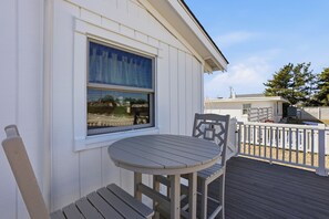 Ein weißes Gebäude mit Fenster, einer Terrasse und einem Tisch mit Stühlen.