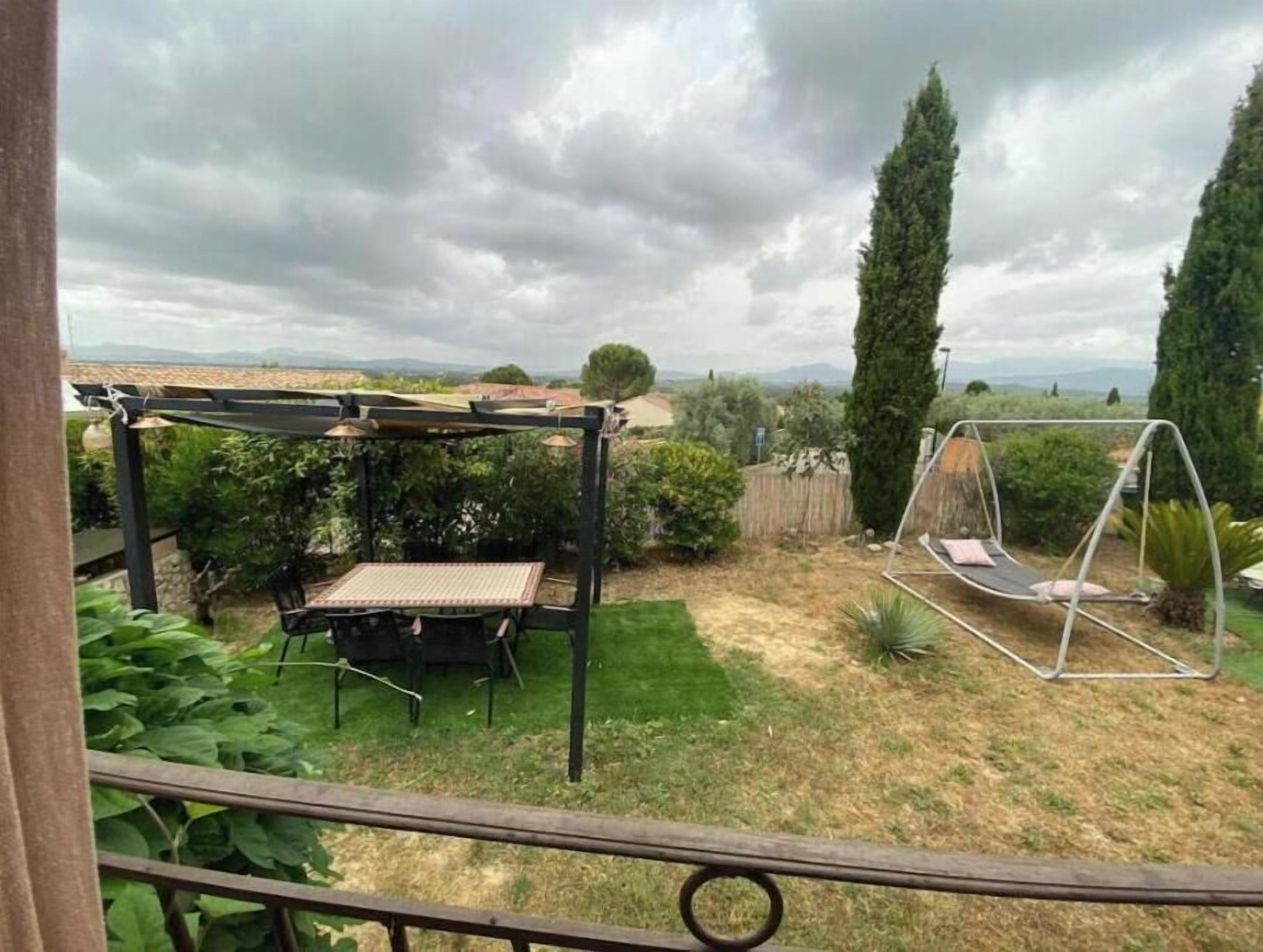 Een terras met een tafel, stoelen, een schommel en een pergola.