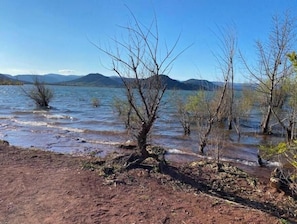 A natural landscape with a body of water, trees, and mountains in the background.