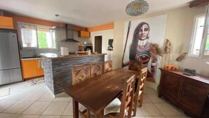 Une cuisine moderne avec un coin repas, un grand tableau et un lustre.