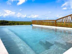 Une piscine aux eaux cristallines, dotée d’une terrasse en bois et offrant une vue sur l’horizon.