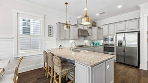 A kitchen with a large island, stainless steel appliances, and white cabinetry. - Community Pool and Hot Tub Access | LSV (Santa Rosa Beach)
