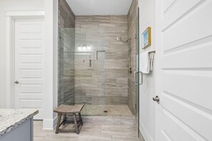 A modern bathroom with a glass-enclosed shower, a wooden bench, and a tiled floor. - Dog Friendly Home with Low-Speed Vehicle, Community Pool and Hot Tub (Santa Rosa Beach)