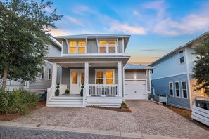 A two-story house with a front porch, garage, and a brick driveway. - Dog Friendly Home with Low-Speed Vehicle, Community Pool and Hot Tub (Santa Rosa Beach)