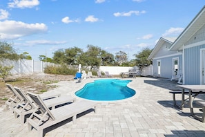 A swimming pool with lounge chairs and a patio table.