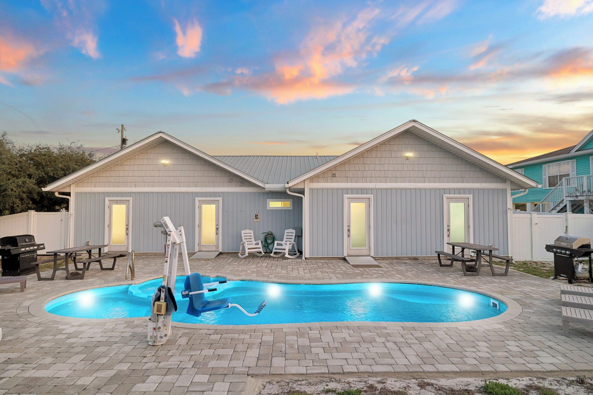 A residential property with a swimming pool, two attached houses, and outdoor furniture.
