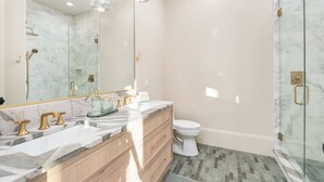 Un baño con tocador de mármol, inodoro y cabina de ducha de cristal.