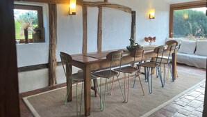 Un comedor rústico con una mesa y sillas de madera, un tapete tejido y vistas al verdor exterior.