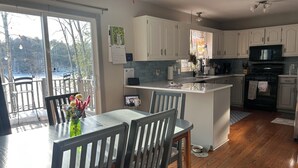 Una cocina moderna con armarios blancos, una isla central y una zona de comedor con mesa y sillas.