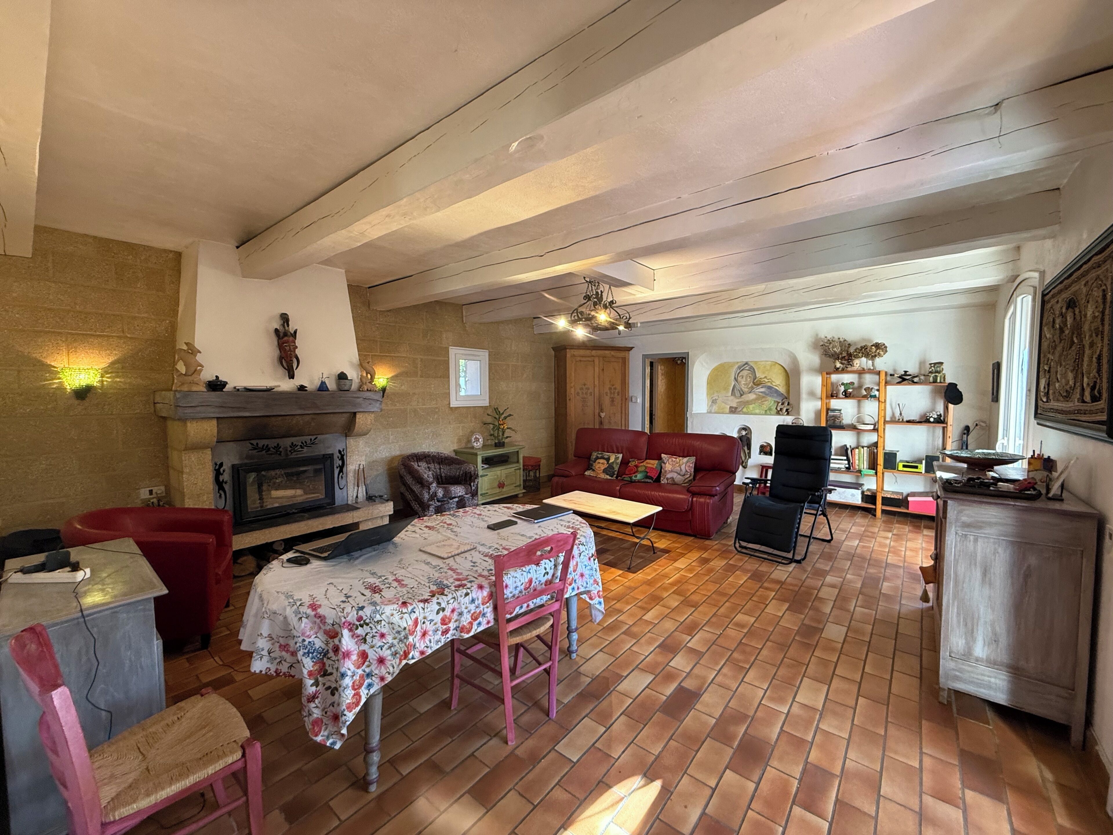 Un salon chaleureux avec une cheminée, une table à manger avec des chaises, un canapé rouge et une bibliothèque.