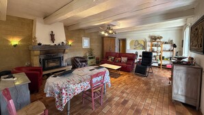 Ein gemütliches Wohnzimmer mit Kamin, einem Esstisch mit Stühlen, einem roten Sofa und einem Bücherregal.