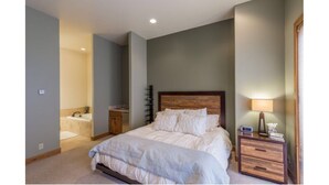 A bedroom with a bed, bedside table, lamp, and a view of the bathroom. - LUXURY 4-BED 5-BATH VILLA ACROSS FROM Mt CB BASE, SLEEPS 12 (Crested Butte)
