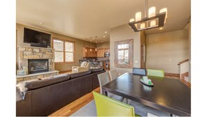 A modern kitchen with a stone fireplace, wooden cabinets, and a dining area with a large table and chairs. - LUXURY 4-BED 5-BATH VILLA ACROSS FROM Mt CB BASE, SLEEPS 12 (Crested Butte)