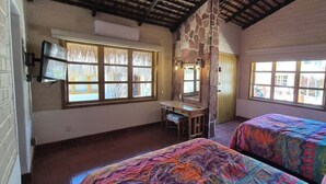 Ein Schlafzimmer mit zwei Betten, einem Schreibtisch, einem Spiegel und einer Steinwand.
