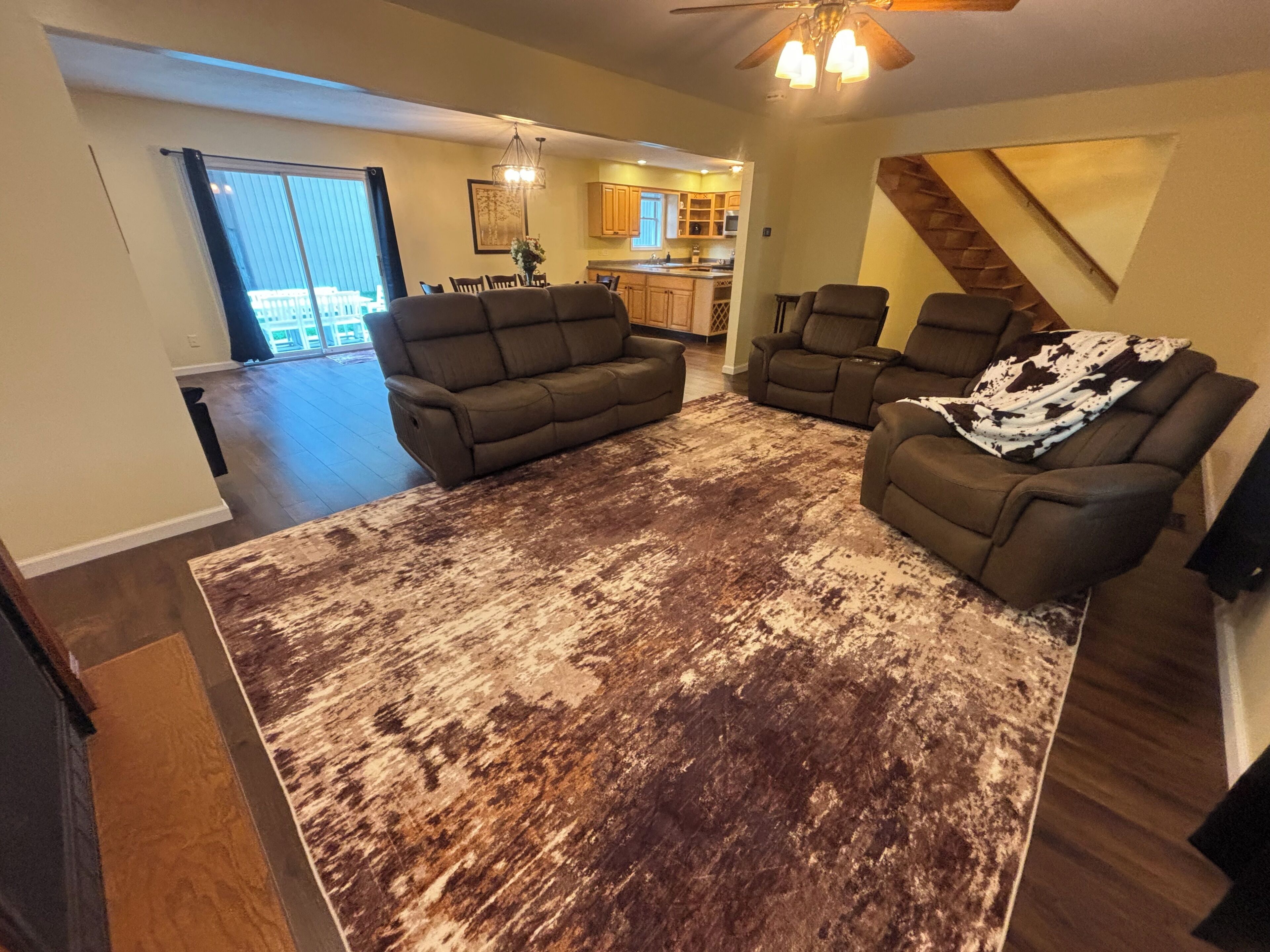 A living room with a large, rustic rug, two sofas, and a ceiling fan.