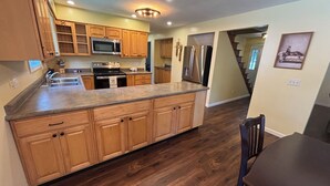 Una cocina con armarios de madera, electrodomésticos de acero inoxidable y piso de madera oscura.
