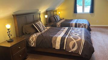 A bedroom with two beds, nightstands, a lamp, and a window.