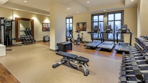 Een fitnessruimte met loopbanden, gewichten en krachtapparaten.