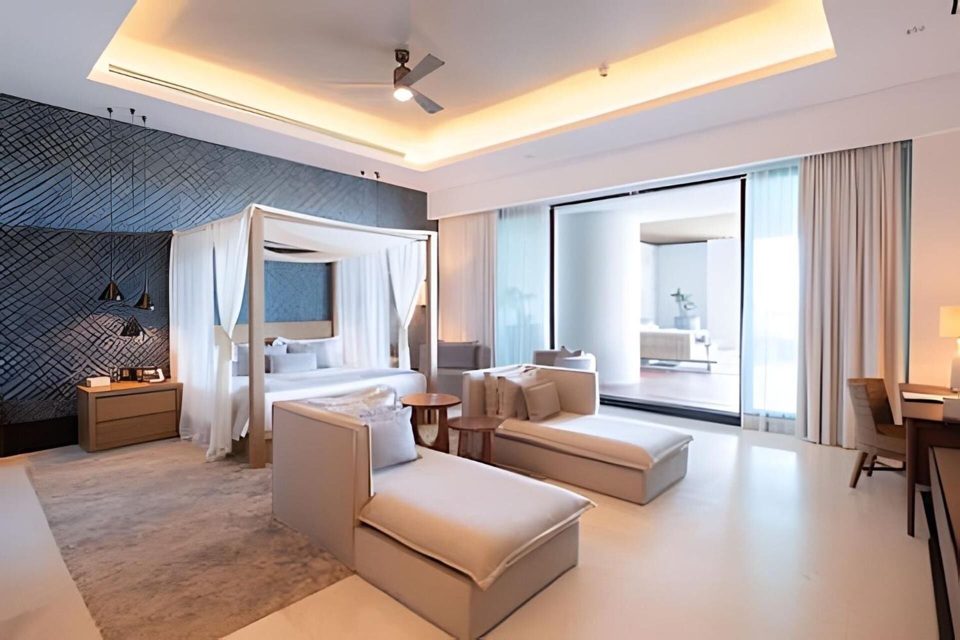 Una habitación de hotel moderna con cama, zona de estar y vistas a la ciudad.